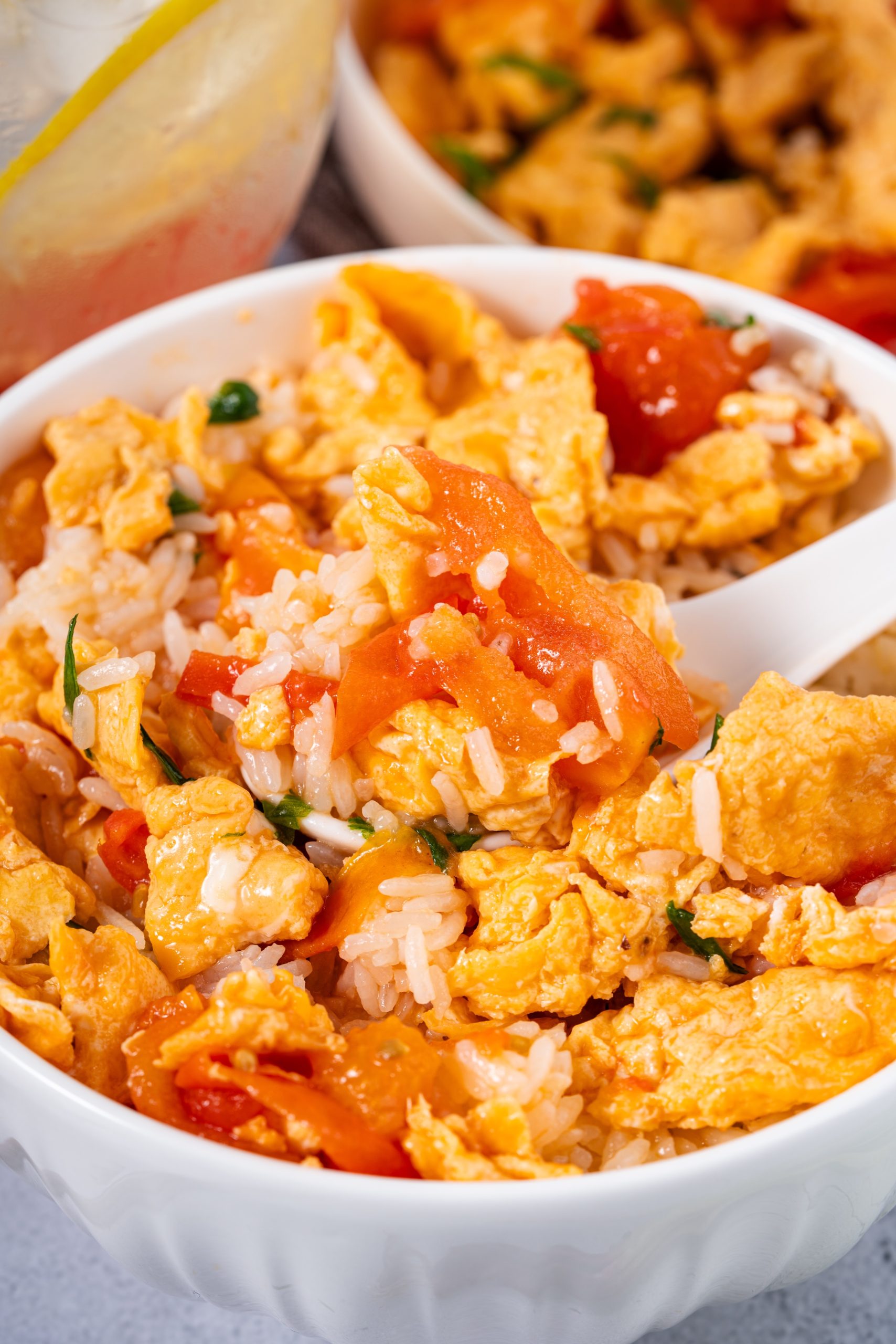 Close-up of Stir Fried Tomato and Egg Recipe served over rice in a white bowl, showing soft scrambled eggs and saucy tomatoes.