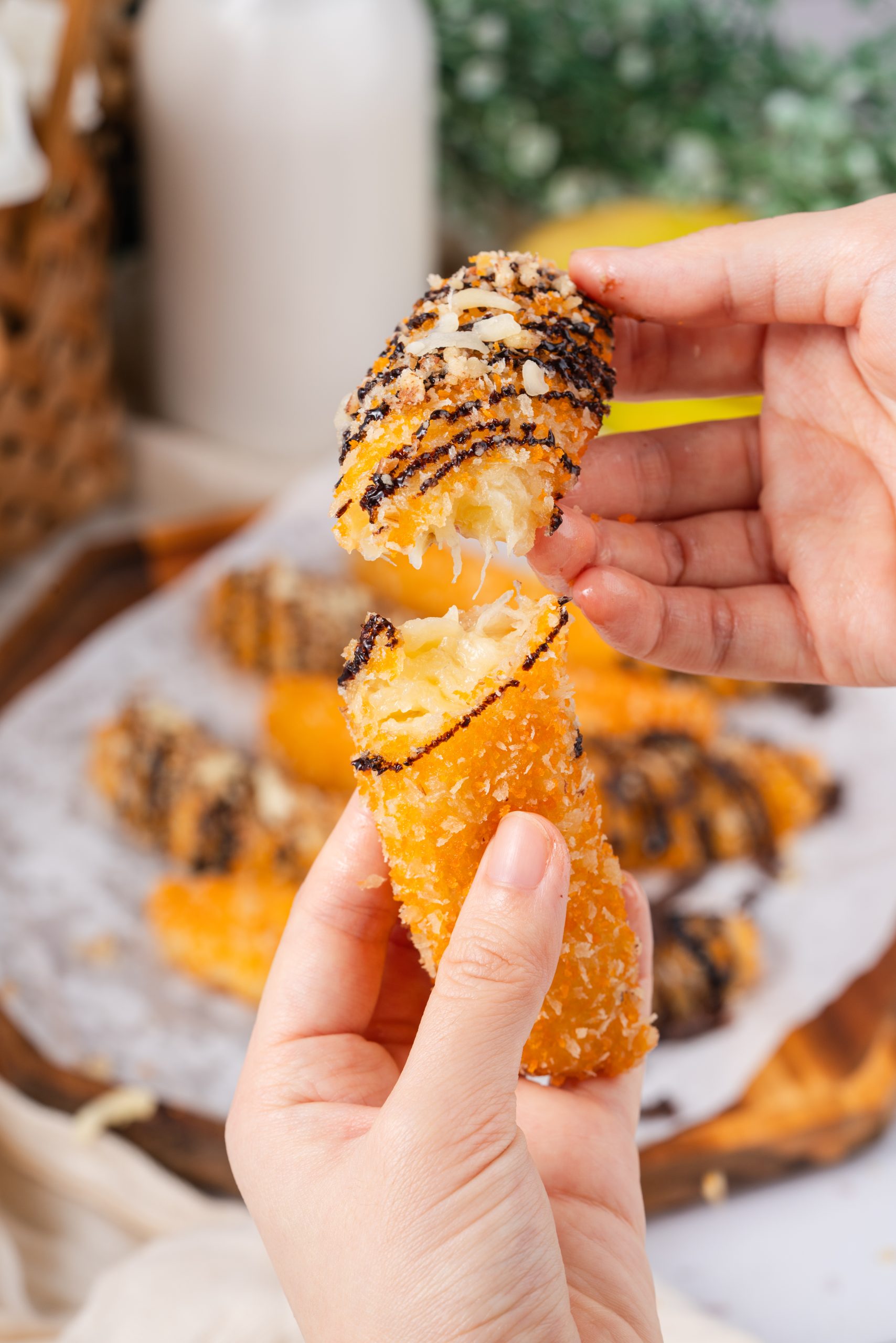 Hands breaking a banana fritter recipe in half, revealing its warm and gooey banana filling with a crunchy golden crust.