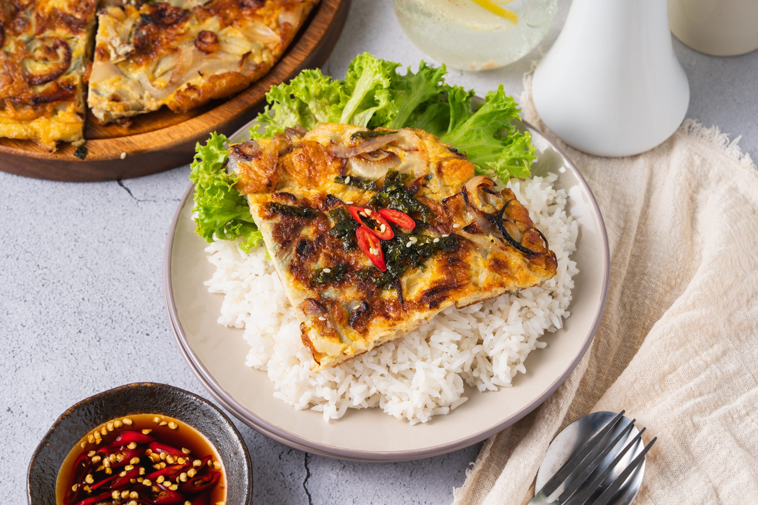 A perfectly cooked Chinese onion omelette recipe served with steamed rice and lettuce, paired with dipping sauce on the side.