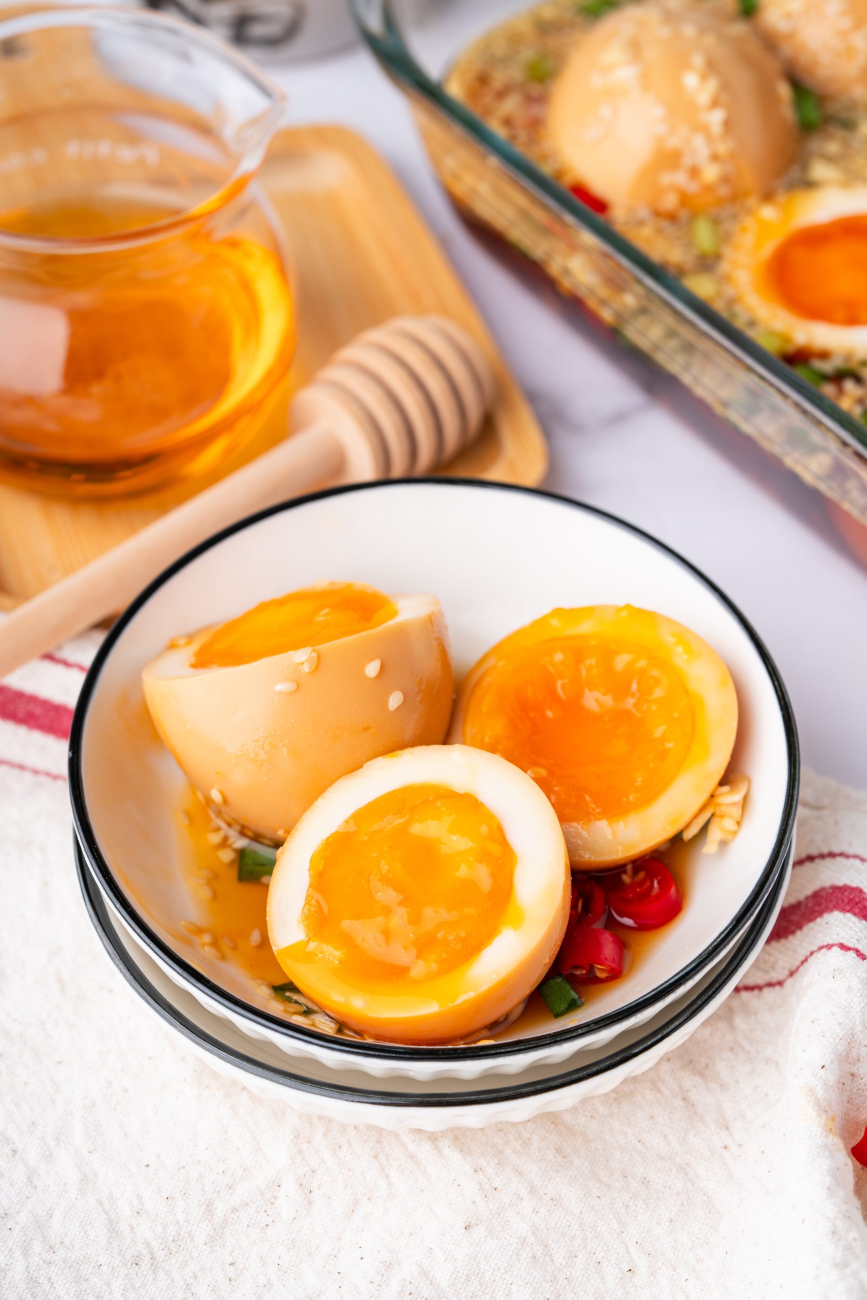 Bowl of Korean Marinated Eggs with jammy yolks, served with sesame, garlic, scallions, and chili marinade