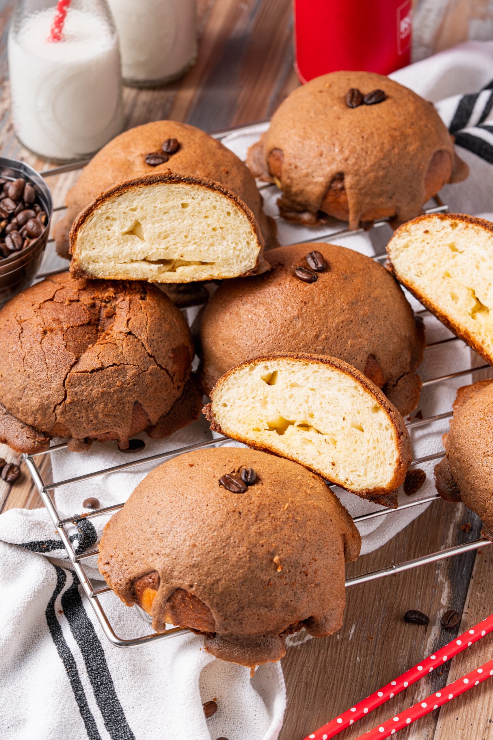 Freshly baked Pappa Roti coffee buns on a cooling rack, showcasing their soft buttery interior and crisp coffee crust, surrounded by milk bottles and coffee beans.
