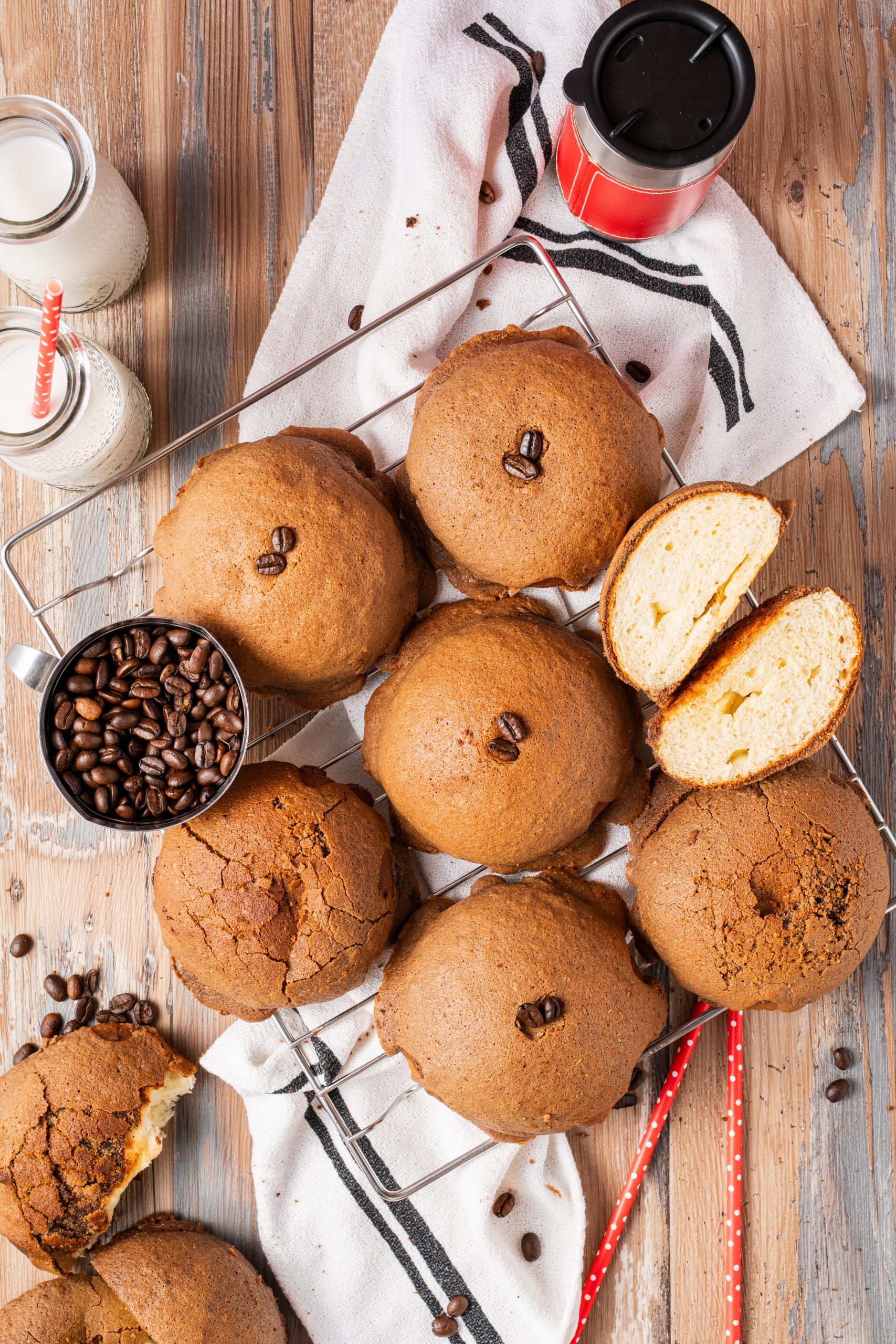 Overhead view of multiple Pappa Roti buns cooling on a wire rack, surrounded by coffee beans and milk bottles.