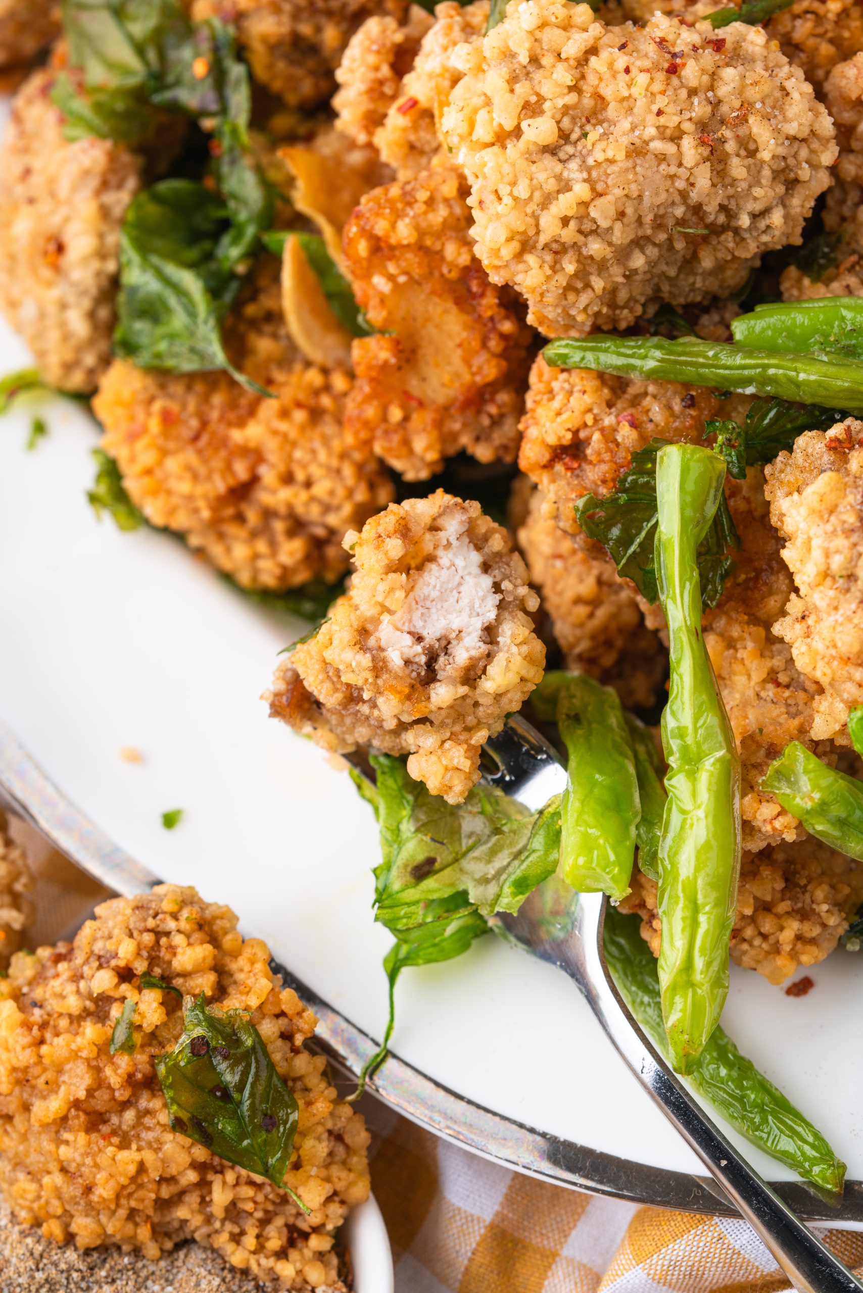 Crispy Taiwanese popcorn chicken showing tender inside and basil garnish.