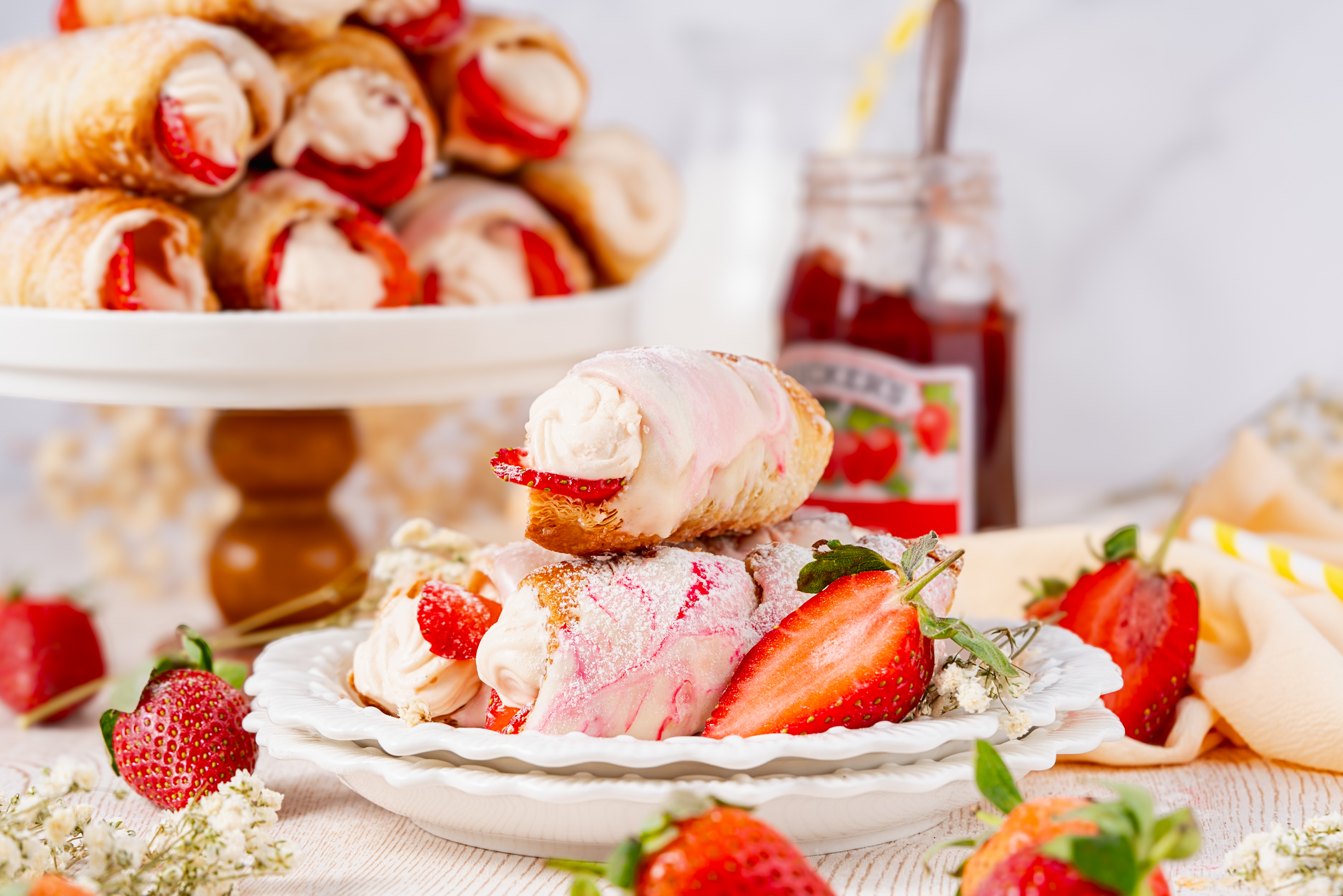 Plate of strawberry Cream Horns filled with cream and fresh fruit, served with powdered sugar and surrounded by ripe strawberries and flowers.