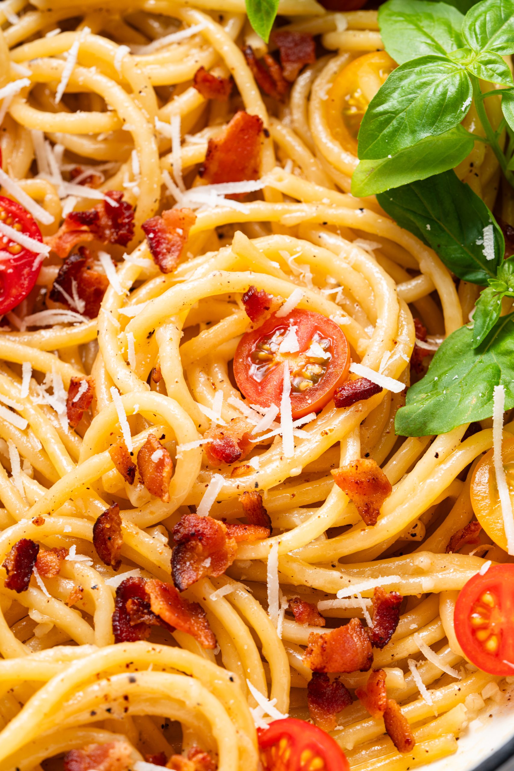 Cacio e Pepe spaghetti coated in a creamy Pecorino Romano and black pepper sauce, garnished with cherry tomatoes and fresh basil.