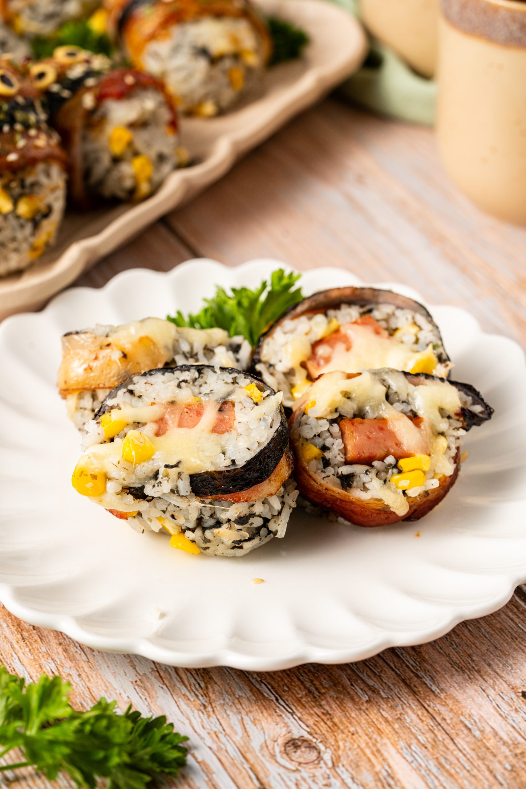 Cheesy bacon-wrapped rice balls sliced open to show corn, seaweed, and melted cheese filling