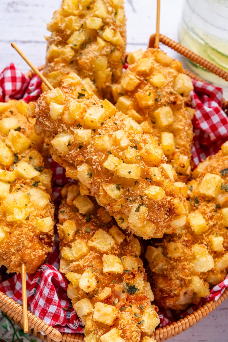 Close-up of crispy Korean corn dog covered in fried potato cubes, showcasing crunchy texture and golden brown coating.