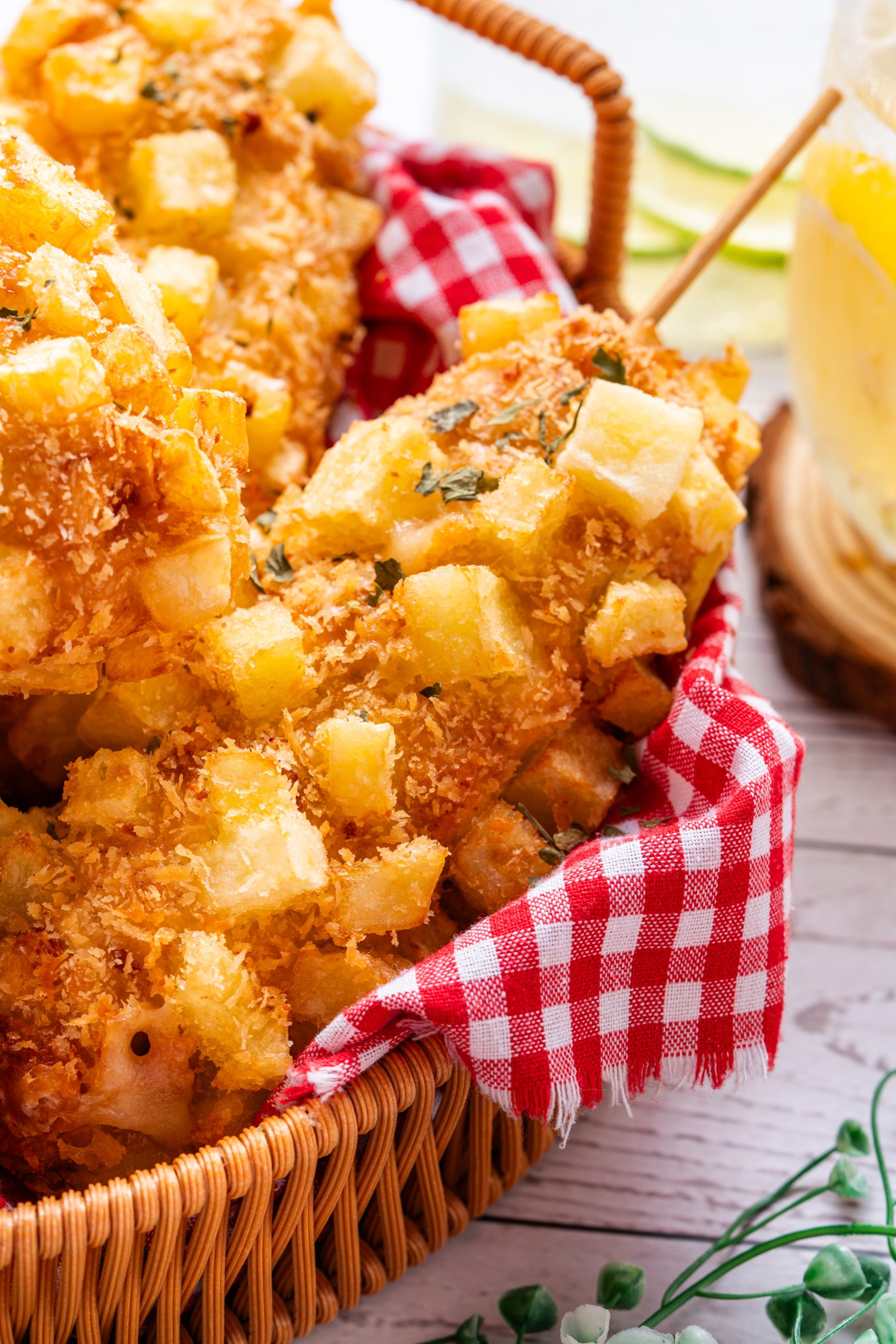 Hand holding a Korean corn dog on a stick, featuring a deep-fried potato crust with crisp texture and golden color.