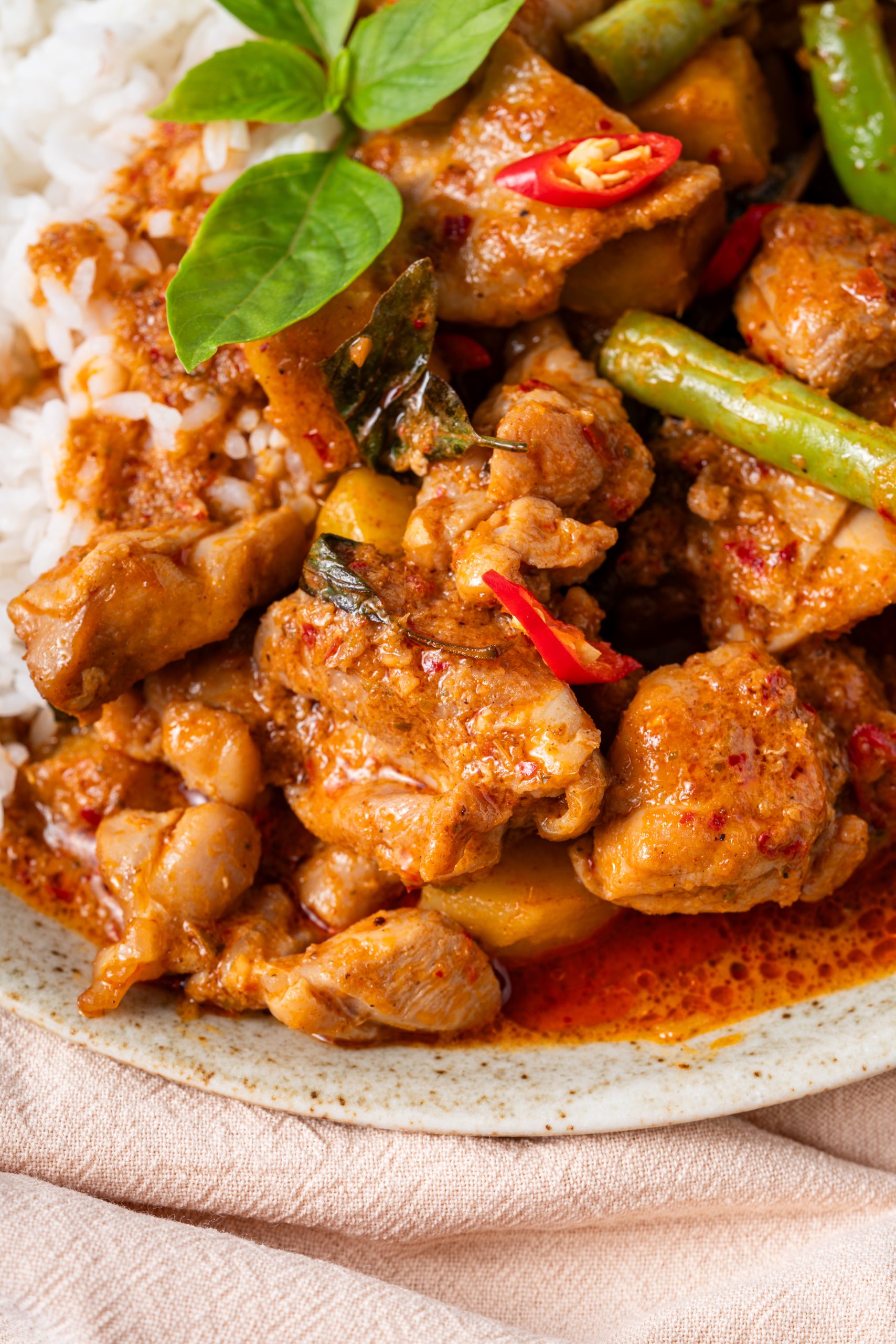 Chicken Panang curry with tender chicken pieces in rich Thai red coconut curry sauce, green beans, red chili slices, and fresh basil served over steamed jasmine rice.
