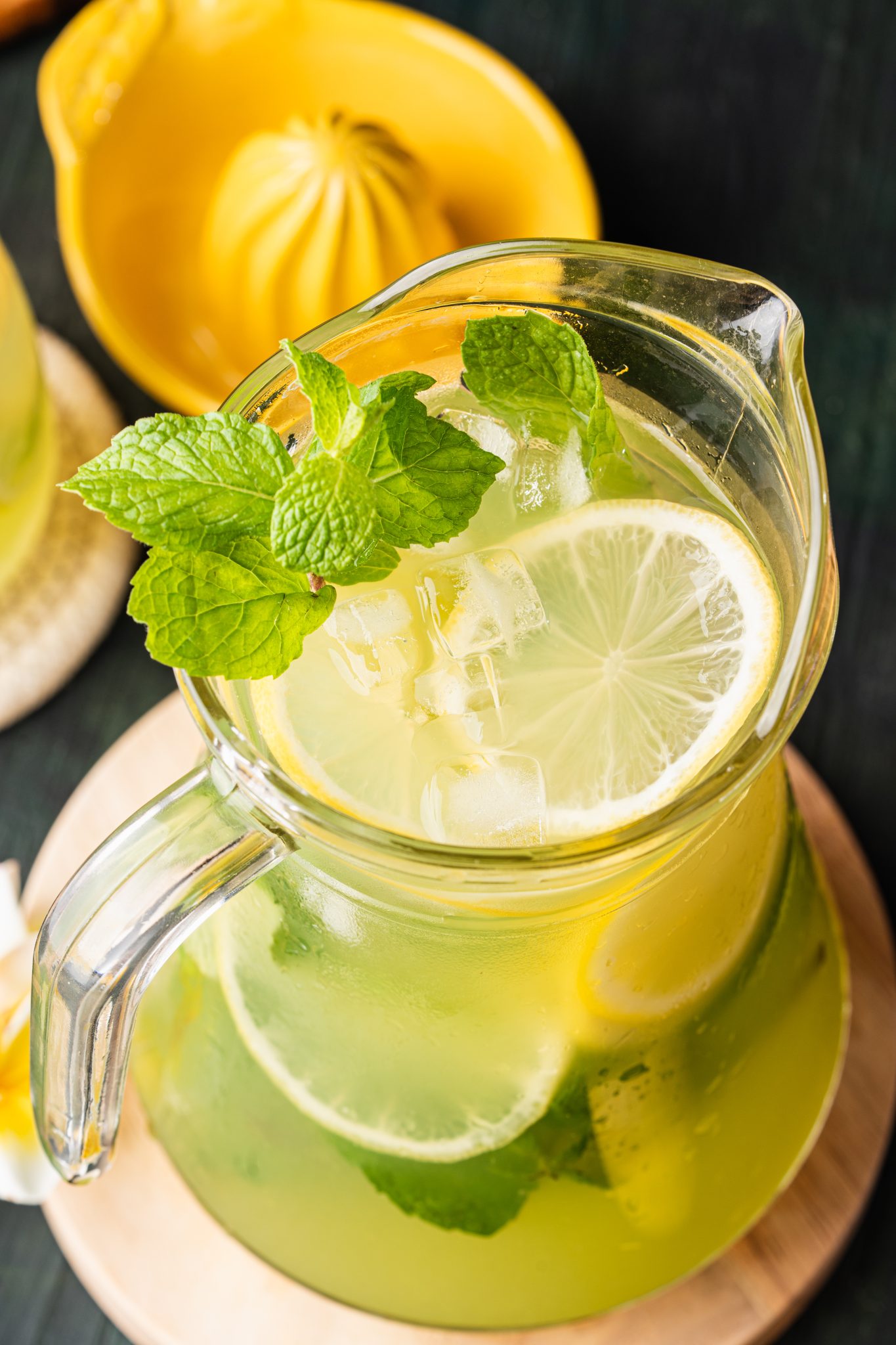 Close-up overhead view of cucumber lemonade in a glass pitcher with lemon slices, mint leaves, and ice.
