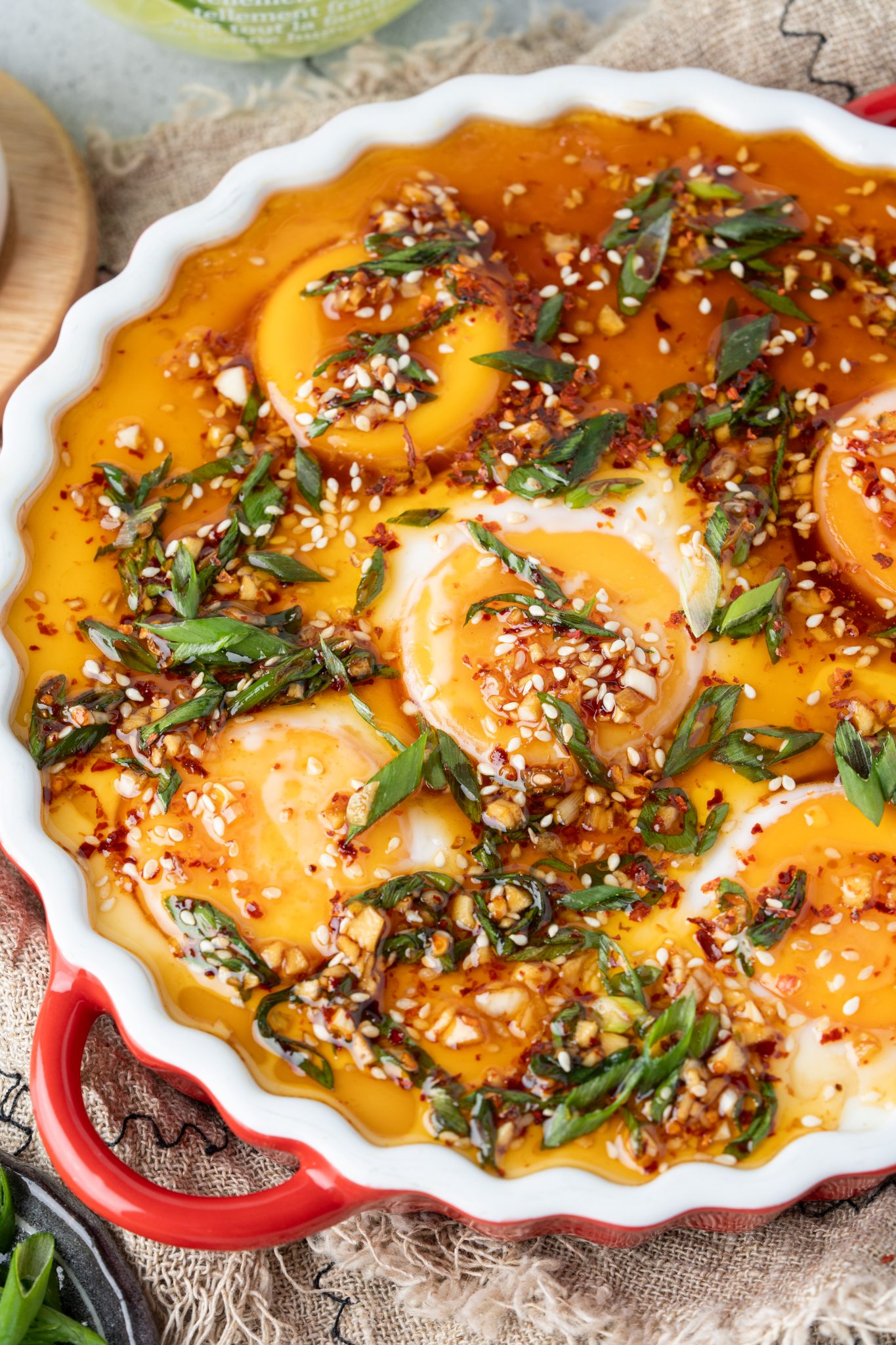 Close-up of smooth and creamy Chinese steamed egg custard topped with chili flakes, sesame seeds, and fresh scallions.