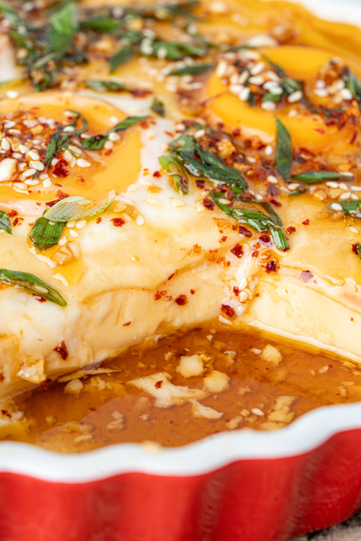 Close-up of ultra-smooth double steamed eggs with savory broth, chili oil, sesame seeds, and scallions.