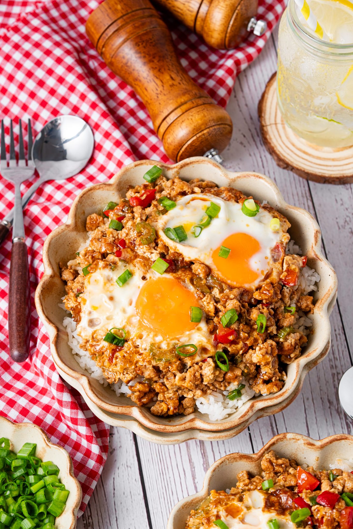 Minced meat and egg rice bowl with soft egg yolks, red peppers, and scallions over fluffy white rice.