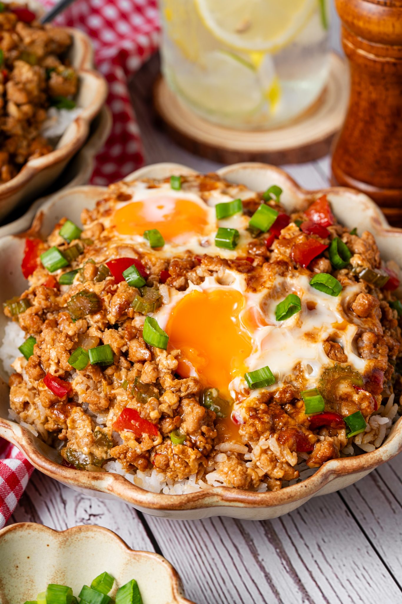 Rice bowl topped with saucy minced meat, fried eggs, red peppers, and fresh scallions.